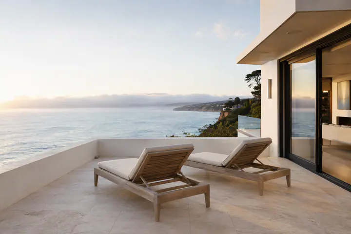 A coastal terrace at morning, loungers on the deck and the Pacific beyond