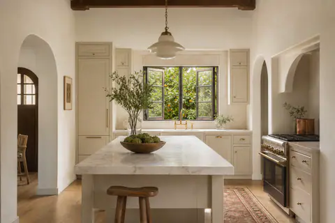 Kitchen with a long honed-marble island and a casement window over the sink